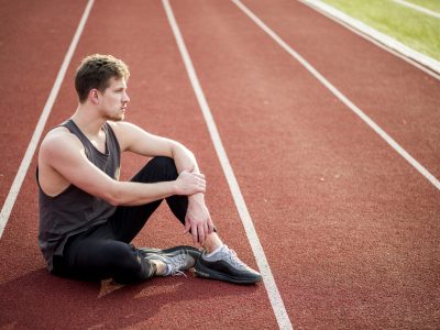 contemplated-young-male-athlete-sitting-race-track.jpg